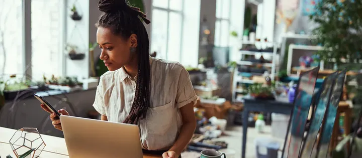 A small-business owner working at a laptop in their shop